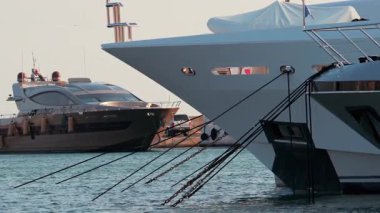 Halatları ve metal zincirleri kapatın. Limanda lüks bir yatı güvence altına alın. Arka planda bulanık su ve kayıklar olsun.