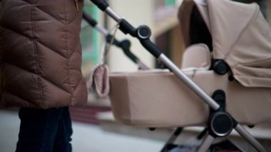 Renkli bir şehir caddesinde yürürken bej bir bebek arabasını iten bir elin yakınına.