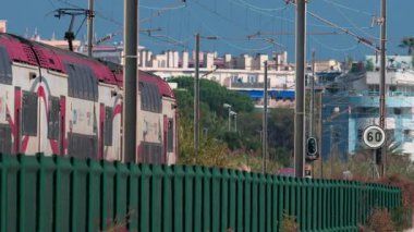 Bölgesel bir çift katlı tren, elektrik hatları ve bitki örtüsüyle çerçevelenmiş Fransız Riviera arazisinde ilerliyor.