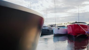 Gün batımında bir marinada demirlemiş kırmızı ve siyah gövdeli lüks teknelerin yakınına.