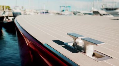 Parlak güneş ışığıyla marinada çekilen, metalik kramponlu, parlak kırmızı, lüks bir tekne güvertesinin yakınında.