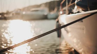 Altın güneş ışığı, sakin bir suda yüzen bir yatın kenarında parıldıyor.