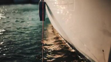 Altın güneş ışığı, sakin bir suda yüzen bir yatın kenarında parıldıyor.