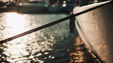 Altın güneş ışığı, sakin bir suda yüzen bir yatın kenarında parıldıyor.