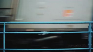 Yumuşak arkaplan renklerine sahip mavi metal bir çitin arkasından geçen trenin bulanık hareketi