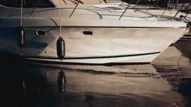 Durgun suda güneş ışığını yansıtan beyaz bir yatın yakınında.