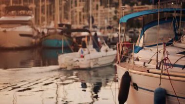 Altın saat boyunca yat limanında dizilmiş zarif yelkenliler, akşam güneşini yansıtan sakin sular.