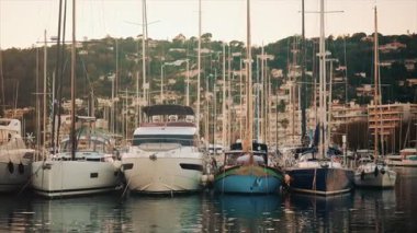 Altın saat boyunca yat limanında dizilmiş zarif yelkenliler, akşam güneşini yansıtan sakin sular.