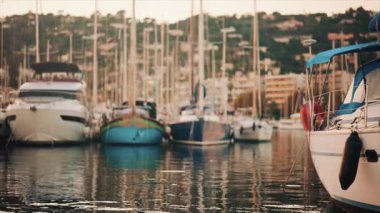 Altın saat boyunca yat limanında dizilmiş zarif yelkenliler, akşam güneşini yansıtan sakin sular.