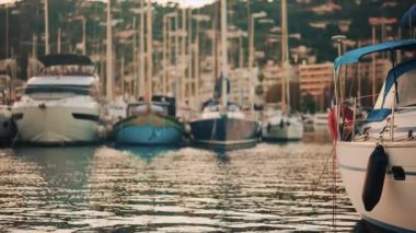 Altın saat boyunca yat limanında dizilmiş zarif yelkenliler, akşam güneşini yansıtan sakin sular.