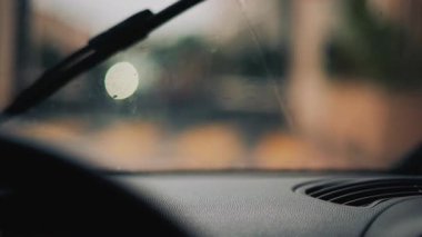 Yağmurda giden bir arabanın içinden ön camdaki damlaları silerken.