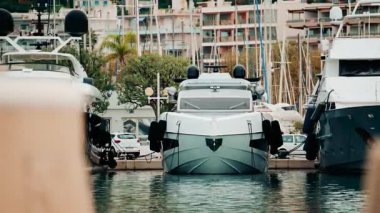 Bir marinaya demirlemiş modern beyaz bir yat, ön taraftan görülüyor.