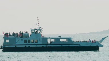 Cannes, Fransa - 3 Ekim 2025: Yolcu feribotu berrak gökyüzü altındaki parlak turkuaz sulardan geçiyor