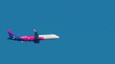 Cannes, Fransa - 6 Ekim 2025: Pembe ve mavi bir yolcu uçağı şehrin üzerinde açık mavi gökyüzüne doğru uçuyor