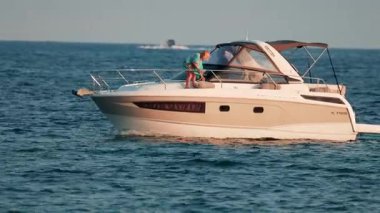 Modern beyaz bir yat, berrak gökyüzünün altında mavi denizde sorunsuzca yol alır.