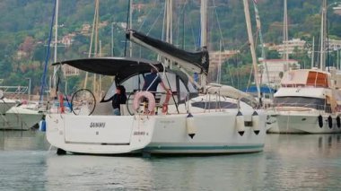 Cannes, Fransa - 12 Ekim 2025: Sakin bir günde bir marinadan ayrılırken beyaz yelkenliyi süren bir adam