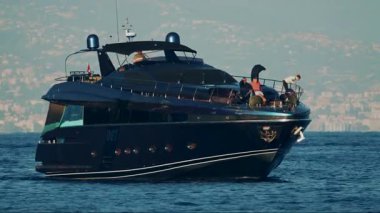 Cannes, Fransa - 16 Ekim 2025: Sakin denizi manzaralı bir sahil kenti arka planıyla geçen zarif siyah yat