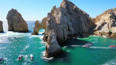 Cabo San Lucas 'ın görkemli kemerinin ve etrafındaki uçurumların açık mavi gökyüzünün altında insansız hava aracı görüntüsü.