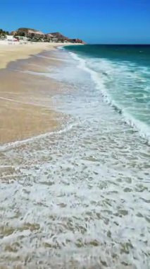 Los Cabos Costa Azul Plajı 'ndaki açık mavi gökyüzünün altında turkuaz dalgaların hava aracı görüntüsü. Dikey