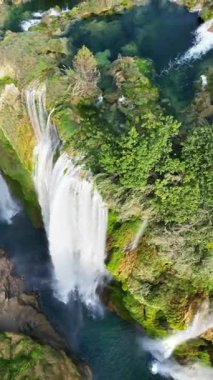 Tamul Şelalesi 'nin hava aracı görüntüsü aşağıdaki turkuaz bir havuza yeşil uçurumlardan dökülüyor. Dikey