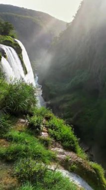 Tamul Şelalesi 'nin hava aracı görüntüsü aşağıdaki turkuaz bir havuza yeşil uçurumlardan dökülüyor. Dikey