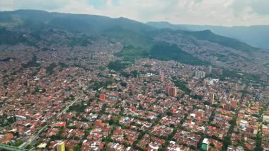 Medellin, Kolombiya 'nın hava aracı görüntüsü yeşil dağlarla çevrili yoğun kentsel alanı yavaş çekim gösteriyor.