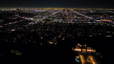 Los Angeles 'ın gece gökyüzünün altında parlayan insansız hava aracı görüntüsü, şehir merkezindeki gökyüzü, parlayan caddeler ve trafik ile çevrili.