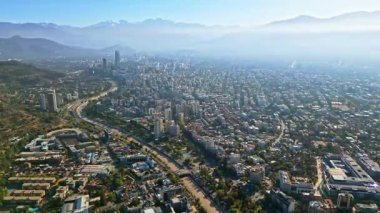Santiago, Şili 'nin yoğun kentsel yayılımının hava aracı görüntüsü, Andes' in uzak tepeleriyle çevrili puslu bir sabah gökyüzünün altında.