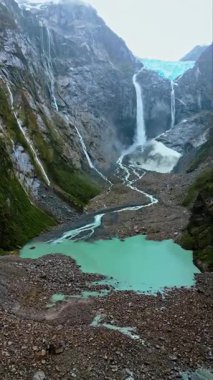 Patagonya 'daki sarp kayalıklardan dökülen bir şelalenin havadan drone görüntüsü. Dikey