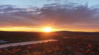 Hava aracı görüntüsü Moldova kırsalını gün batımında tarla desenleri ve uzakta parlayan bir nehirle gösteriyor.