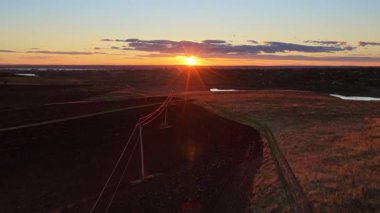 Dönen bir nehrin hava aracı görüntüsü Moldova 'nın kayan tepeleri ve uzak köyleri üzerindeki sıcak günbatımı ışığını yansıtıyor.