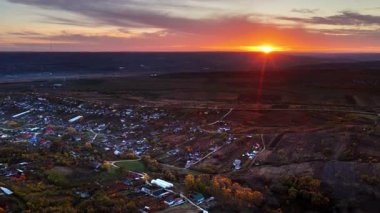 Güneş 'in Moldova köyünün üzerinde batışını gösteren hava aracı manzarası.