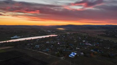 Moldova köyü ve kıvrımlı nehrin renkli bir günbatımı altında hava aracı görüntüsü zaman aşımı