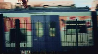 Cannes, Fransa - 1 Kasım 2025: Renkli grafiklerle bulanık yüksek hız treni metal bir çitin arkasından geçiyor, hareket, seyahat ve kentsel ulaşım altyapısı