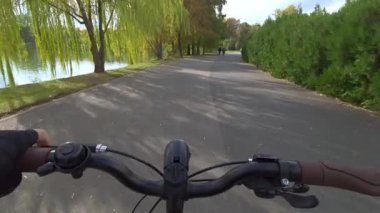 Cannes, Fransa - 5 Kasım 2025: Ağaçlar ve çalılarla kaplı göl yolu boyunca bisiklet süren ilk kişi görüntüsü
