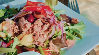 Renkli bir salatayı ton balığı, patates, zeytin, kırmızı soğan, biber ve karışık yeşillikle kapat.