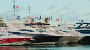 Cannes, France - November 5, 2025: Row of sleek motor yachts moored in a modern marina under a bright daytime sky with flags fluttering above the decks