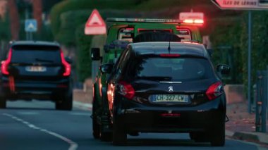 Cannes, Fransa - 7 Kasım 2025: Alacakaranlıkta Fransız banliyösü boyunca giden bir çekiciye yüklenmiş siyah bir hatchback arabası