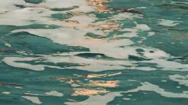 Sıcak ışık altında hareket eden ve parıldayan köpüklü deniz suyunu kapat