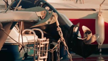 Bir tekne pervanesinin sinematik görüntüsü kırmızı bir gövdenin yanında, su yüzeyindeki canlı renkleri yansıtıyor.