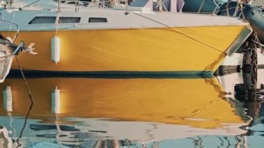 Beyaz ve sarı tekne marinadaki yansımasıyla kenetlendi.