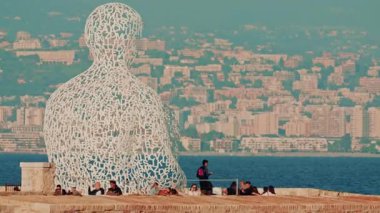 Antibes, Fransa - 9 Kasım 2025: Denize bakan ünlü beyaz harf heykelinin manzarası, insanların yakınlarda dinlenmesi ve arka planda Nice şehrinin manzarası