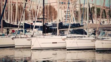 A dense line of white sailboats is moored side by side in a marina