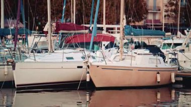 Yelkenleri sarılı ve emniyete alınmış iki komşu yelkenliye yaklaşın. Yansımaları aşağıdaki suda usulca görünür.