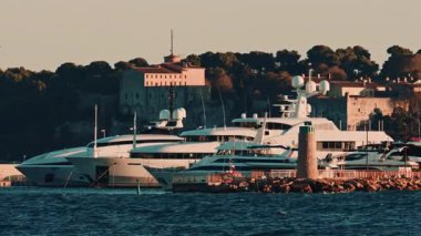 Cannes, Fransa - 17 Kasım 2025: Norveç Viva yolcu gemisi, ön planda güçlü dalgalar ve rüzgar sörfçüleriyle kaplı küçük bir yarımadanın arkasında