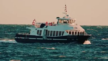 Cannes, Fransa - 18 Kasım 2025: Yolcu feribotu dalgalı sularda yüzüyor, kameraya doğru ilerliyor, rüzgar sörfçüleri uzaktan görülüyor.