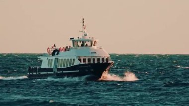 Cannes, Fransa - 18 Kasım 2025: Yolcu feribotu dalgalı sularda yüzüyor, kameraya doğru ilerliyor, rüzgar sörfçüleri uzaktan görülüyor.