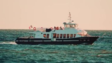 Cannes, Fransa - 18 Kasım 2025: Akdeniz XII adlı yolcu feribotunun sıcak gün batımı ışığı altında dalgalı sularda yüzüşü