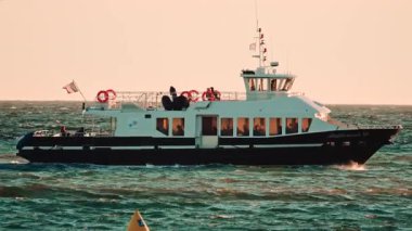 Cannes, Fransa - 18 Kasım 2025: Akdeniz XII adlı yolcu feribotunun sıcak gün batımı ışığı altında dalgalı sularda yüzüşü