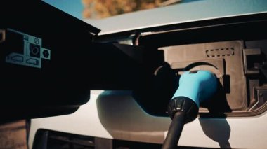 Bir elektrikli aracın kabloya bağlı şarj portunun yakın çekim görüntüsü